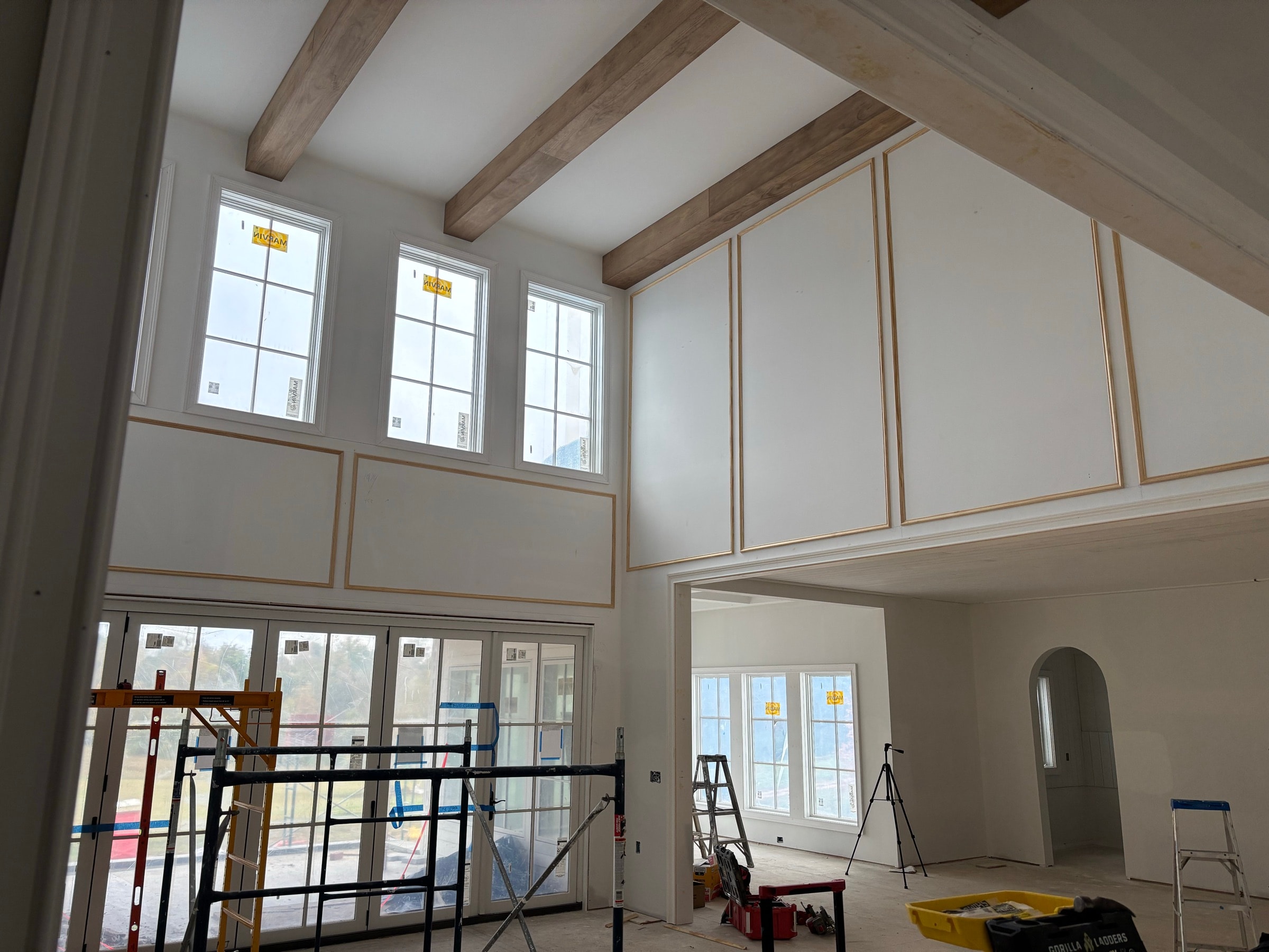 Bright vaulted great room with board paneling and tall windows